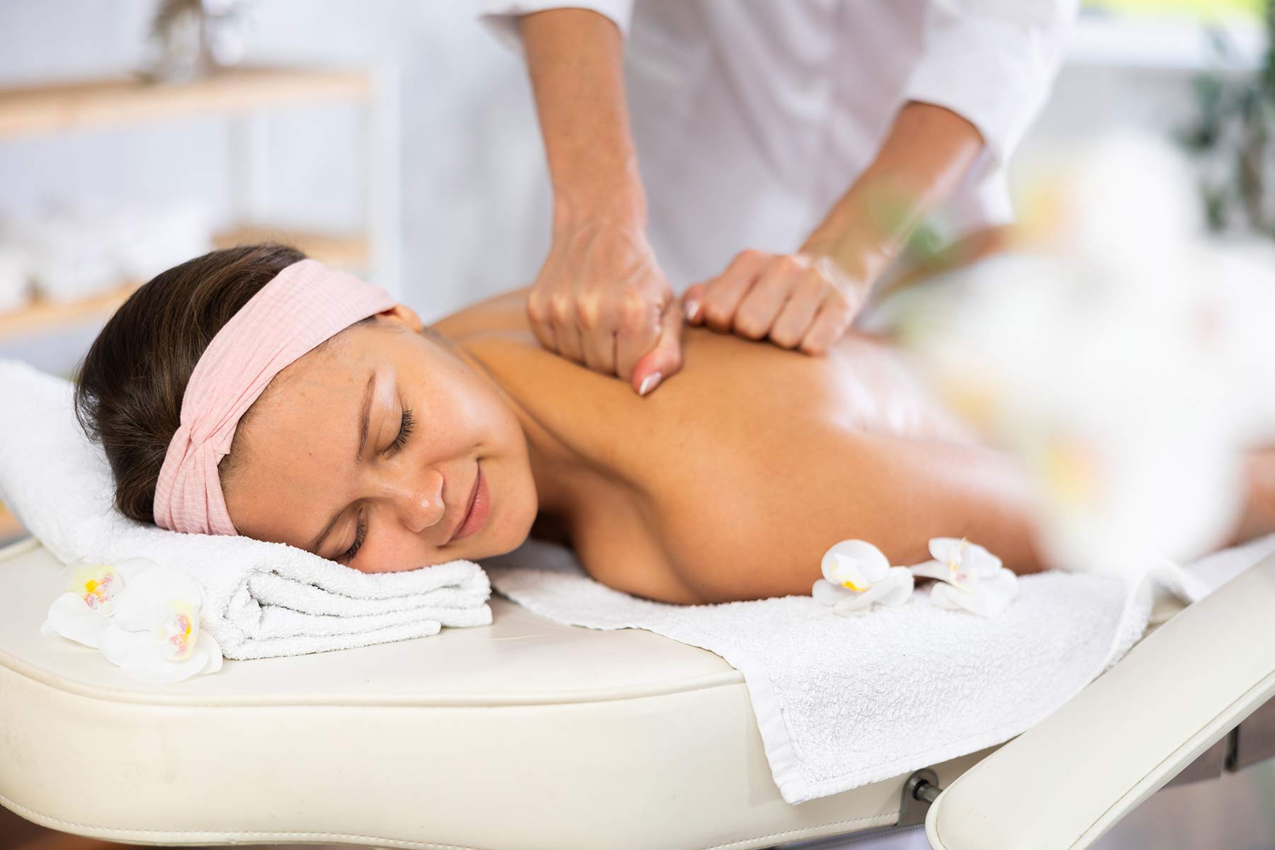 A massage therapist performing a Swedish massage on a client's back using gentle strokes